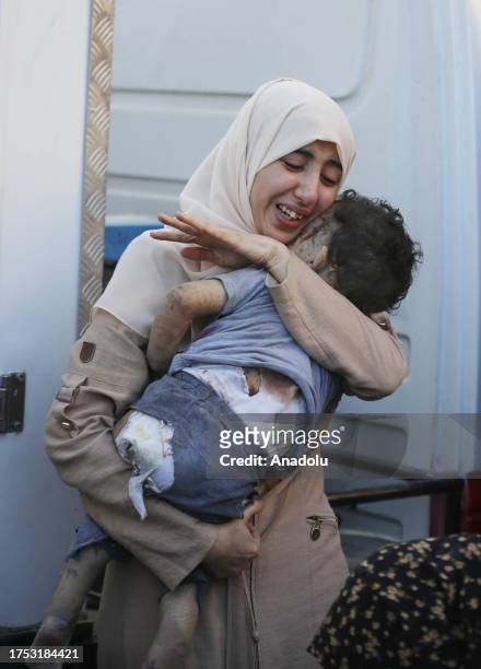 Woman mourns as she carries body of her child who lost his life after Israeli attacks at Al Aqsa Martyrs Hospital as Israeli attacks continue on the...