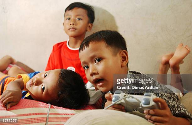 Garil Arnanda , Izul Haq , and Dwiga Meza play a game on Playstation January 30, 2003 in Denpasar, Bali, Indonesia. Their father, Aris Munandar, was...