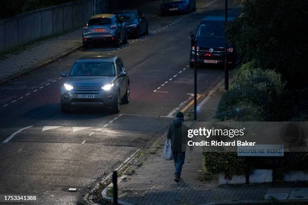 Seen from a high perspective, a man walks down the road at dusk on a residential street in Lambeth, south London, on 27th October 2023, in London,...