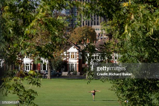 Man stretches and exercises on one leg in Ruskin Park, a south London green space in Lambeth that overlooks the city, on 27th October 2023, in...
