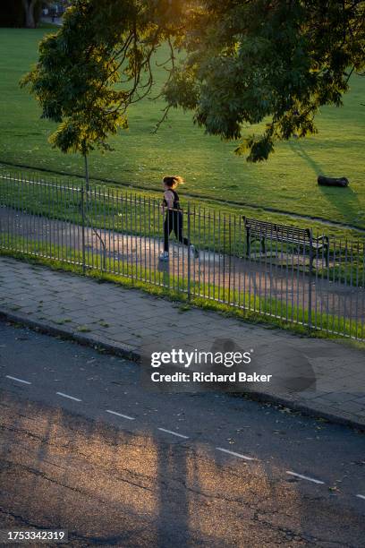 Woman runner speeds through autumn colours in Ruskin Park, a south London green space, on 27th October 2023, in London, England.