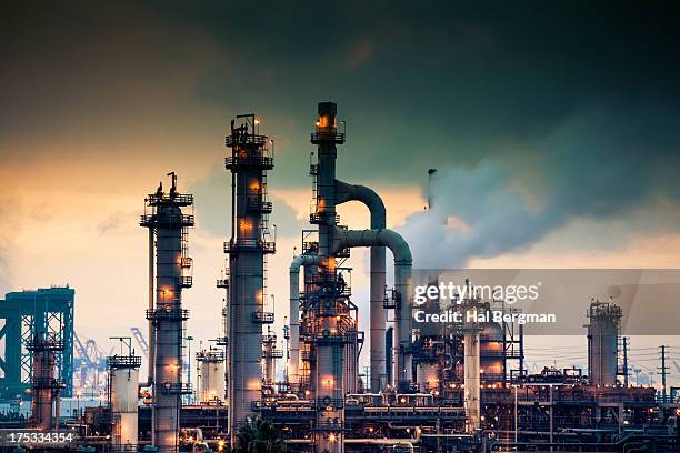 steaming refinery at sunrise - olieraffinaderij stockfoto's en -beelden