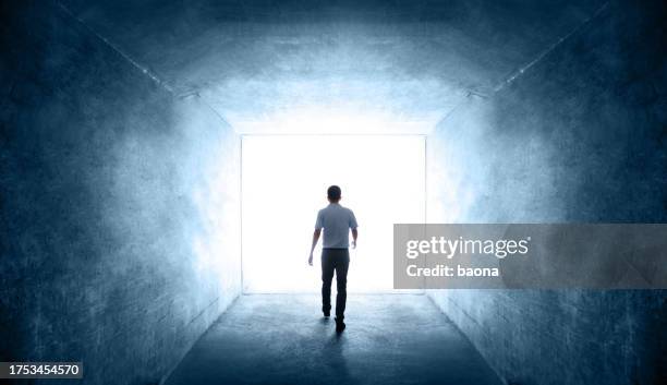 rear view of single young man walking through a dark tunnel - heaven gates stock pictures, royalty-free photos & images