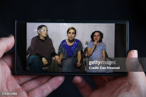 In this photo illustration, a phone displays footage released by Hamas today showing three hostages - Rimon Buchshtab Kirsht , Danielle Aloni , Lena...