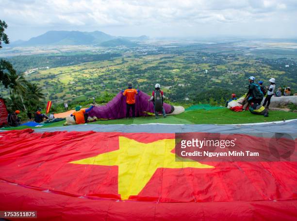 a paraglider shaped like the vietnamese flag is preparing to take off in the golden rice fields, an giang province - vietnamese flag stock pictures, royalty-free photos & images