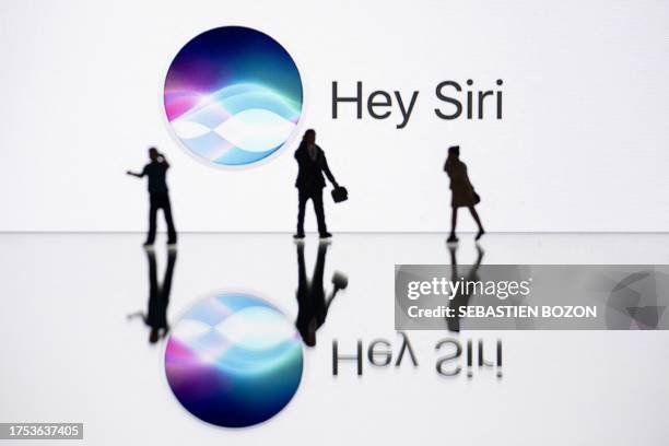 Siri This illustration photograph taken on October 30 in Mulhouse, eastern France, shows figurines next to a screen displaying a logo of Siri, a...