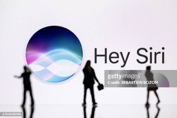 Siri This illustration photograph taken on October 30 in Mulhouse, eastern France, shows figurines next to a screen displaying a logo of Siri, a...