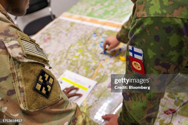 Representatives from the US Army, left, and the Finnish Army, right, inspect a map during a staged fight and evacuation of injured soldiers at a...