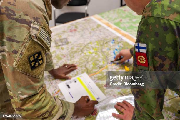 Representatives from the US Army, left, and the Finnish Army, right, inspect a map during a staged fight and evacuation of injured soldiers at a...