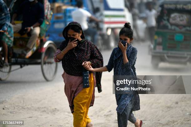 Pedestrians hold their noses to escape the dust on a busy road in Dhaka, Bangladesh, on October 30, 2023.