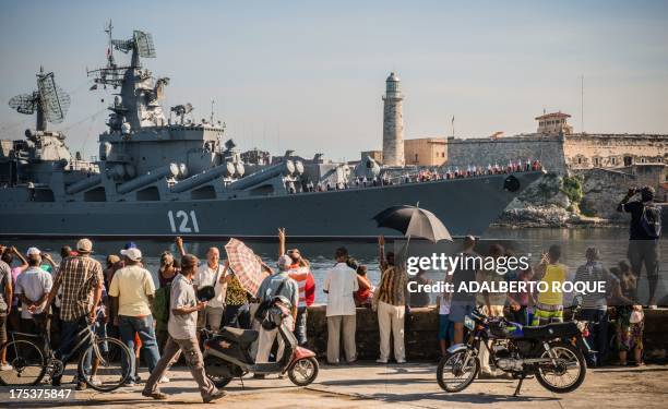 Cubans wave as the "Moskva" Russian guide missile cruiser arrives at Havana's harbour, on August 3, 2013. The vessel is part of a three-ship group in...