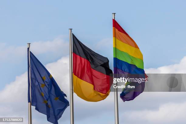 eu-, german- and rainbow(lgbtq+)- flag with blue sky - berlin gay pride stock pictures, royalty-free photos & images