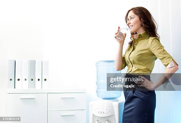 businesswoman having drink from water cooler. - water cooler stock pictures, royalty-free photos & images