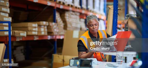 trabajadora de almacén en su mostrador de despacho - manual fotografías e imágenes de stock
