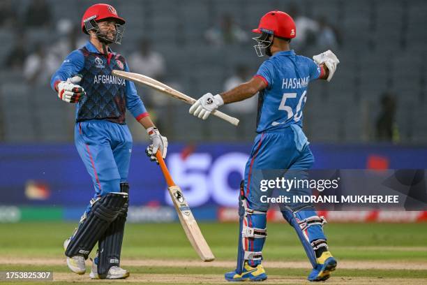 Afghanistan's Azmatullah Omarzai celebrates with his captain Hashmatullah Shahidi after scoring a half-century during the 2023 ICC Men's Cricket...