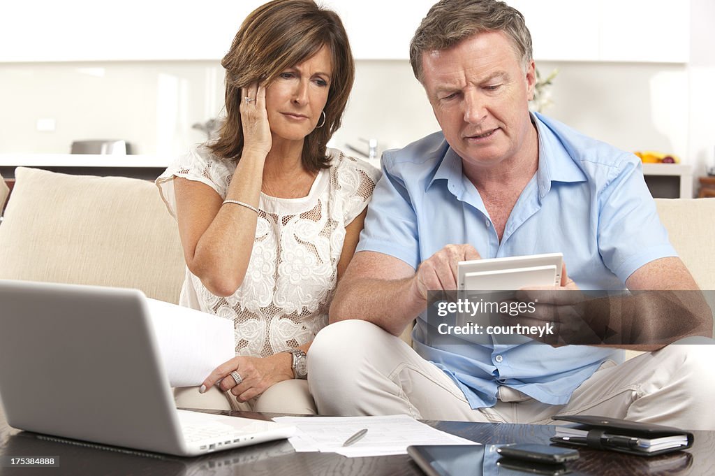 Besorgt Älteres Paar, die Papierkram mit einem Taschenrechner