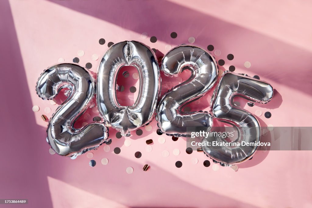 Silver numbers 2025 two thousand twenty five new year balloons in sunlight pink background