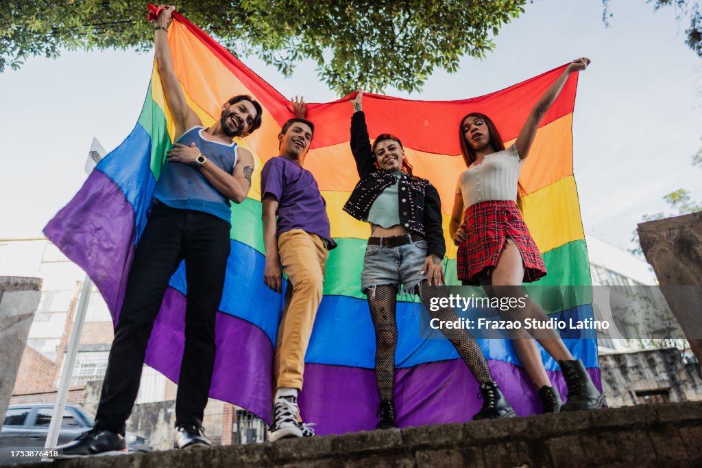 Porträt eines LGBTQIA+-Freundes, der eine Regenbogenflagge im Freien hält