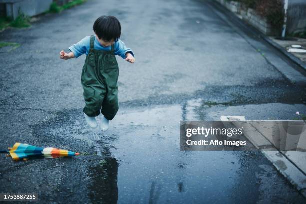 japanese kid playing outside on a rainy day - puddle stock pictures, royalty-free photos & images