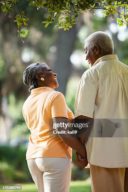 シニアアフリカ系アメリカ人カップル手をつなぐ - african american couple walking park ストックフォトと画像