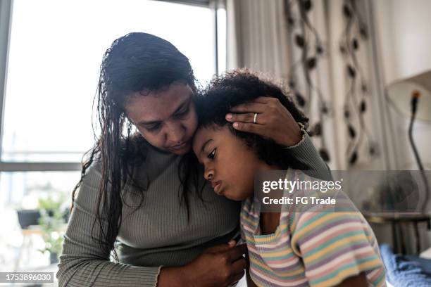 mother embracing sad daughter in the bedroom at home - african american family sad stock pictures, royalty-free photos & images