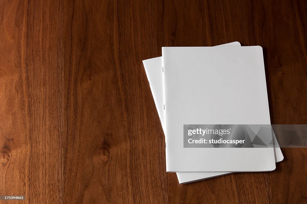 Two blank magazines on a wooden floor