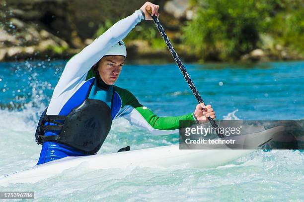 joven macho piragüista en el blanco de agua - canoe rapids fotografías e imágenes de stock