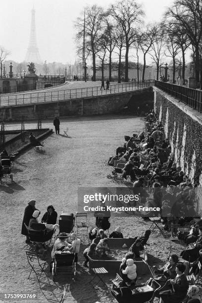 Tandis que des enfants jouent avec le sable du Jardin des Tuileries, les mamans profitent des premiers rayons de soleil à Paris le 9 avril 1964