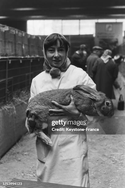 Une agricultrice pose avec un lapin lors du salon à la Porte de Versailles à Paris le 9 mars 1964