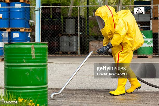 trabajador en traje amarillo hazmat limpieza de tierra - clean suit fotografías e imágenes de stock