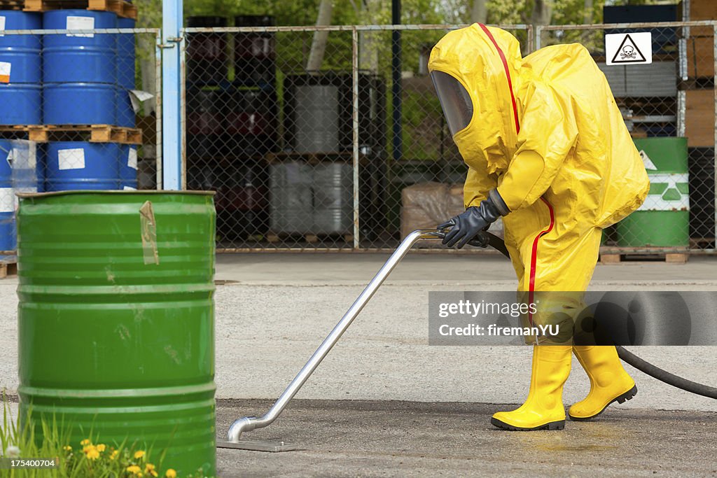 Worker in yellow hazmat suit cleaning ground