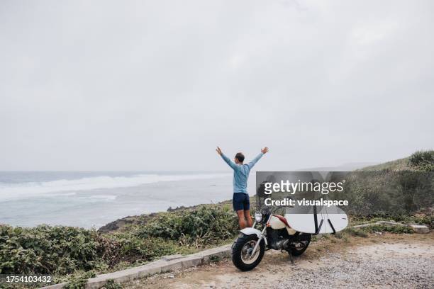 surfista alla ricerca del surfspot giusto con la sua moto - mare moto foto e immagini stock