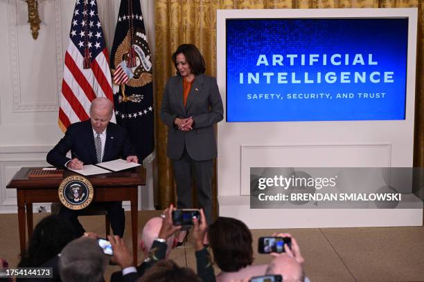 Vice President Kamala Harris looks on as US President Joe Biden signs an executive order after delivering remarks on advancing the safe, secure, and...