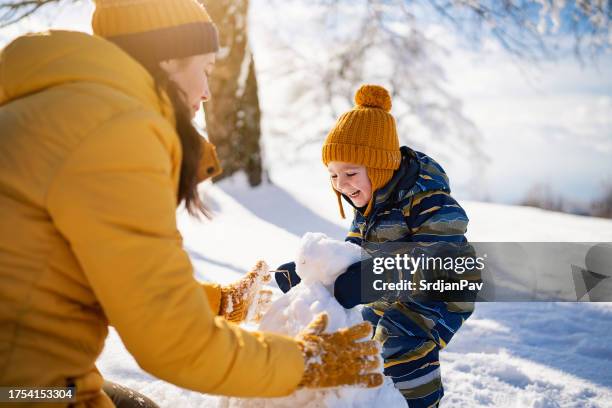 mutter und sohn basteln gemeinsam einen schneemann - family in snow mountain stock-fotos und bilder