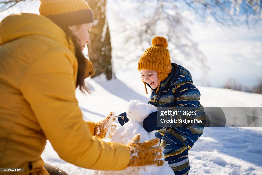 Mom and son making a snowman together