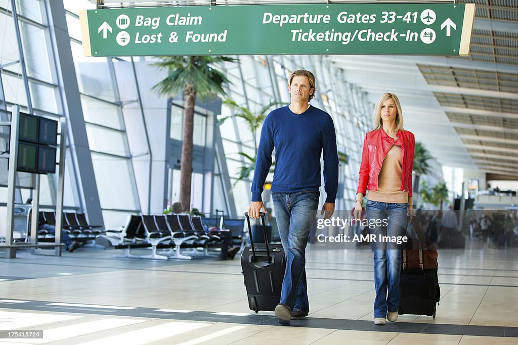 Couple in an airport with suitcases.