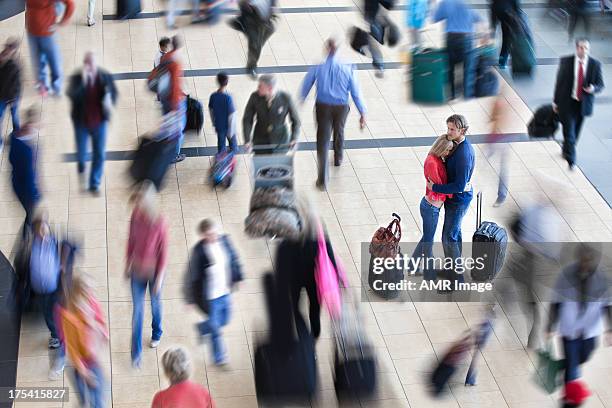 couple embraced in crowded airport - airport crowd stock pictures, royalty-free photos & images