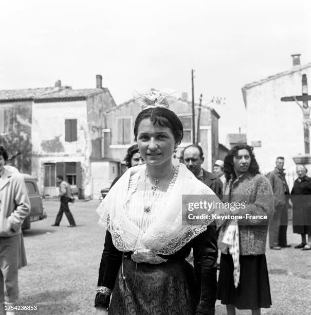 Jeune femme en costume traditionnel dans la rue aux Saintes-Maries-de-la-Mer, le 23 mai 1960.