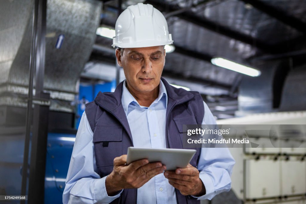 Warehouse supervisor holding digital tablet inside industrial facility