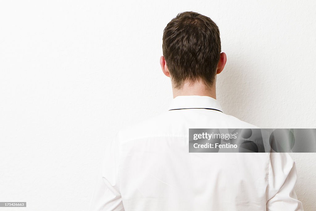 La parte trasera del empresario contra una pared.