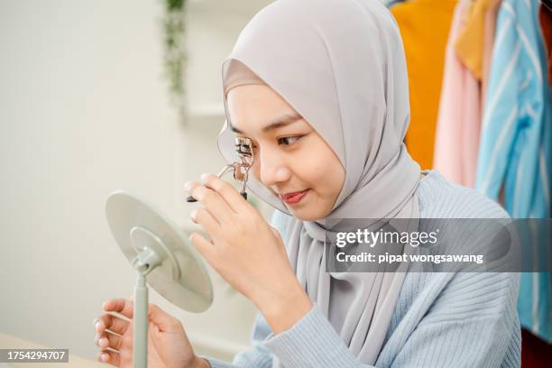 close-up, young muslim woman wearing hijab making up her eyelash with eyelash curler - beauty eye makeup hijab stock pictures, royalty-free photos & images