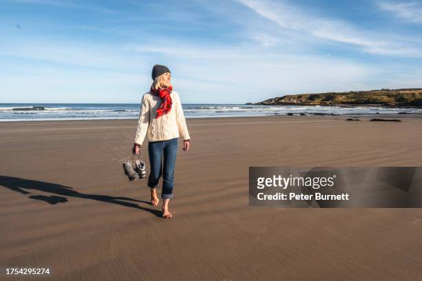 senior woman walking on the beach at sandend, moray, scotland. - moray scotland stock pictures, royalty-free photos & images
