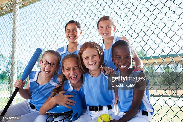 girls softball team sitting in dugout - dugout baseball stock pictures, royalty-free photos & images