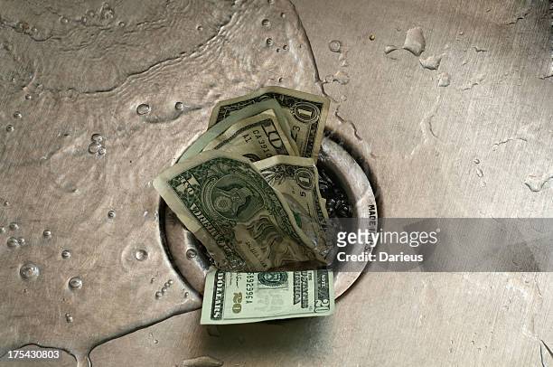 us paper currency, shoved in to the drain of a wet sink  - wasting money stock pictures, royalty-free photos & images