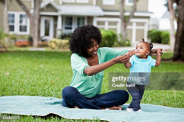 mother helping baby walk - mum sitting down with baby stockfoto's en -beelden