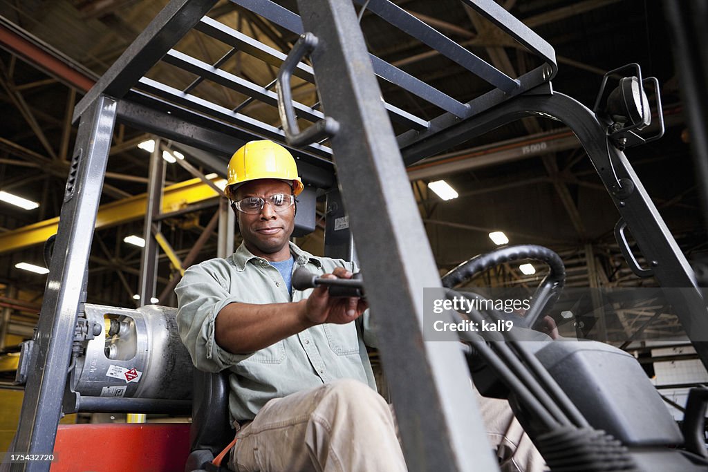 African American worker driving forklift