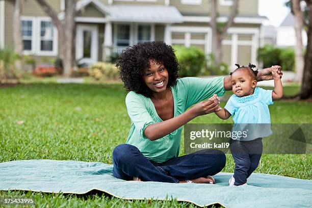 mother helping baby walk - mum sitting down with baby stockfoto's en -beelden