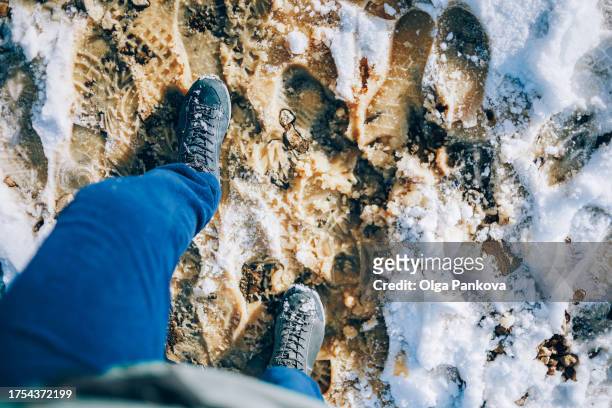 pov first-person view of feet with boots on the snow and a dirty road - pov shoes ストックフォトと画像