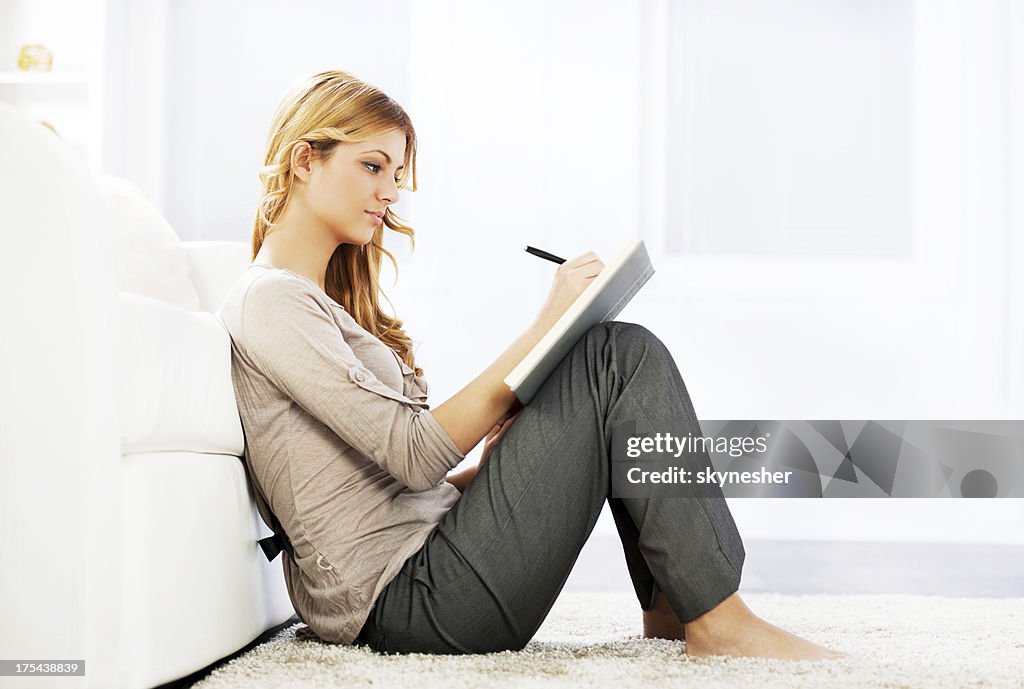 Portrait of a blonde woman writing diary.