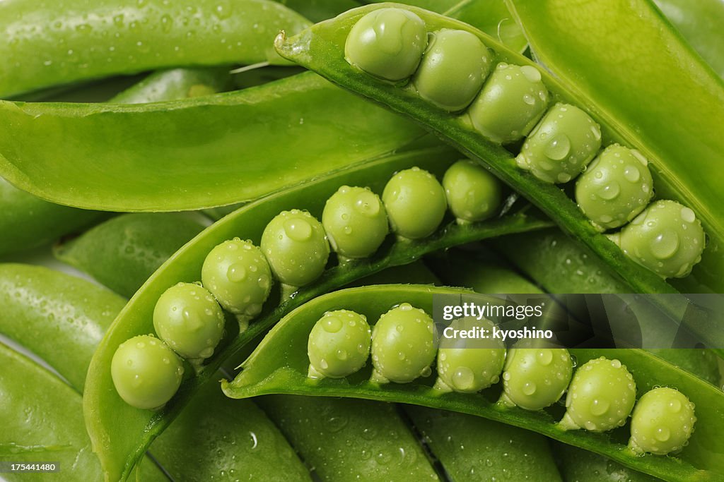 Stacked opened fresh green peas with water droplets